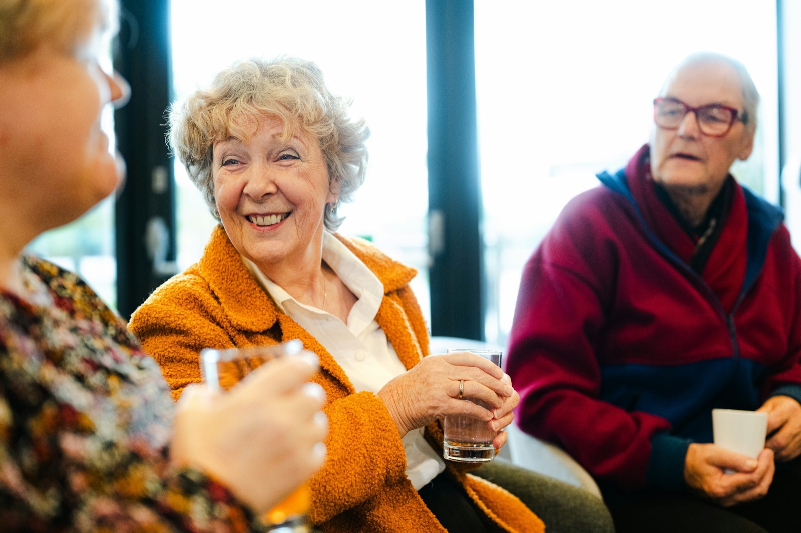 Three friends talking and smiling over coffee